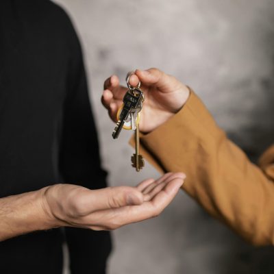 Detailed close-up of one person handing over keys to another, symbolizing a real estate transaction.